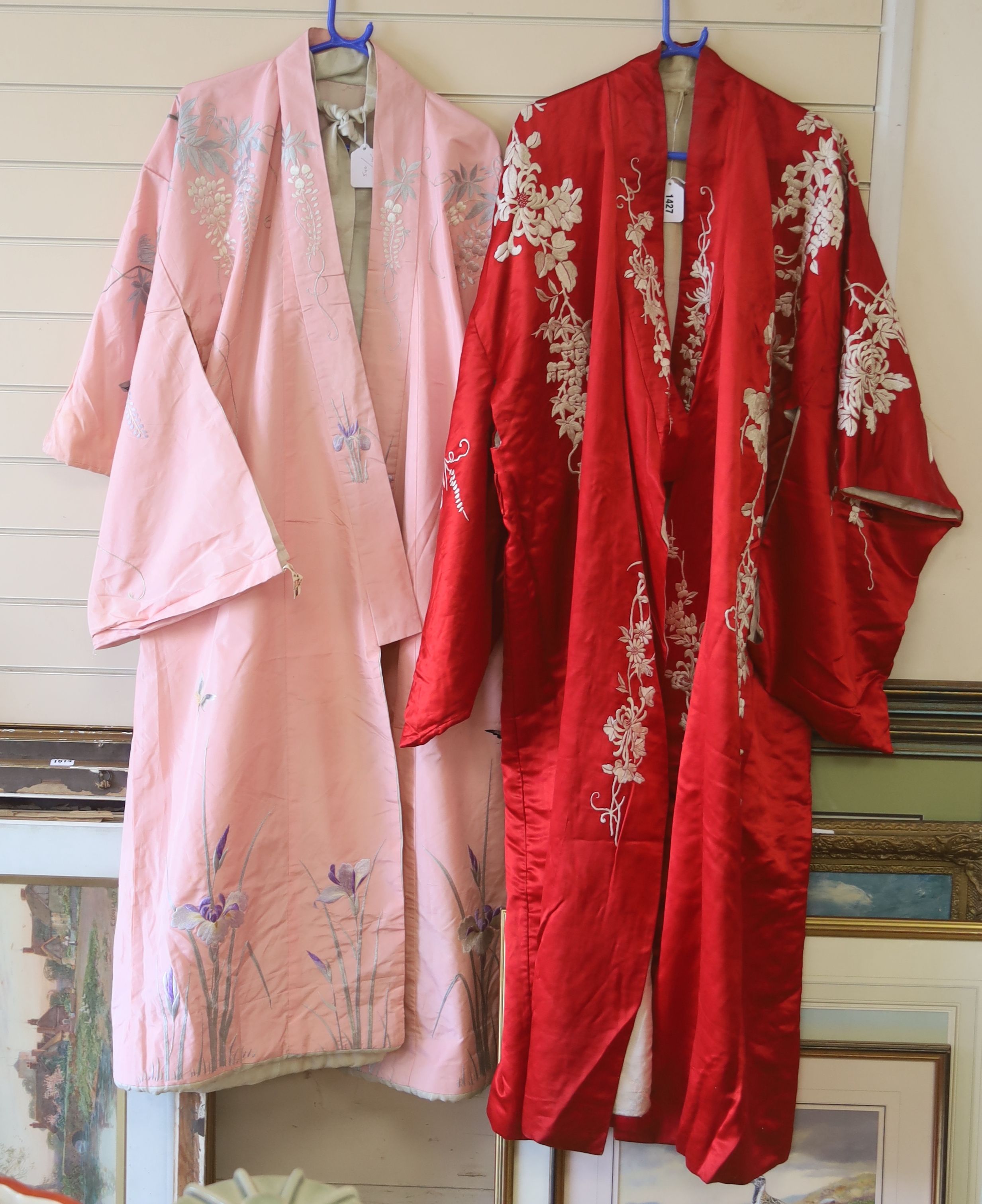 A pink silk Japanese kimono embroidered with wisteria and irises and butterflies, length 140cm, together with a red kimono embroidered with white wisteria and carnations